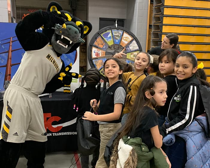 University of Wisconsin Milwaukee Panthers mascot, Pounce, poses with school children who are playing a spin-the-wheel game